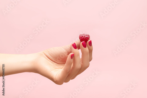 Foto Yound female hand hold red raspberry