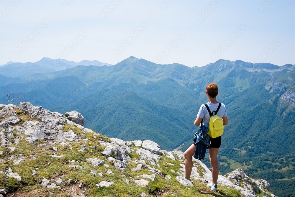 Hiker woman looks at the beautiful landscape from the top of a mountain