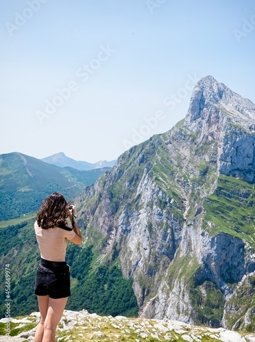 Rear view of a young woman taking photos of a rocky peak