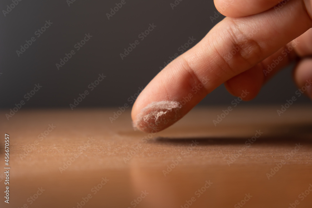 Touching the dust on a surface of furniture with finger Touching the dust on a surface of furniture with finger