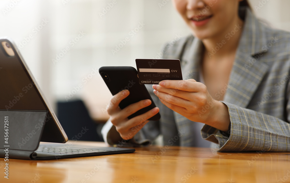 Close up of woman hand holding credit card and using smart phone for online shopping and payment. Online shopping and payment online concept Close up of woman hand holding credit card and using smart phone for online shopping and payment. Online shopping and payment online concept