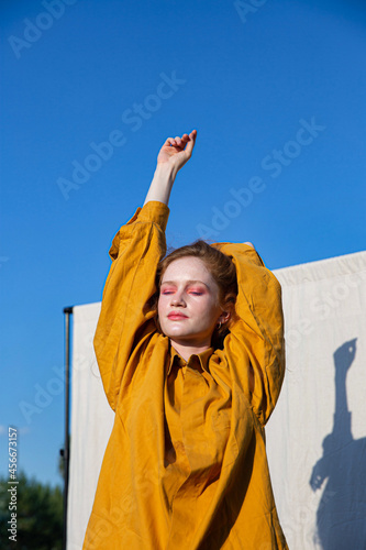 European girl with bright makeup in yellow clothes with blue sky behind