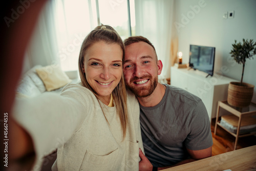 Caucasian couple taking selfie in lounge with cellular device