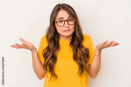 Young caucasian woman isolated on white background doubting and shrugging shoulders in questioning gesture. photo