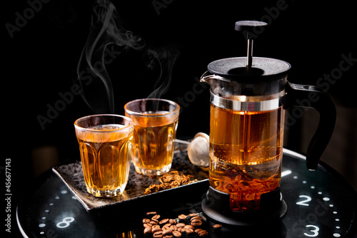 coffee flower tea  in a tea pot and glass on a wooden board on a black background.tea concept in a glass teapot against a background
