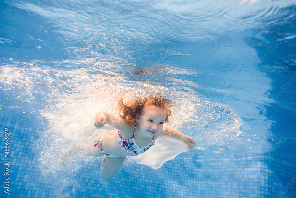 Little girl swimming under water in paddling pool. Diving. Learning ...