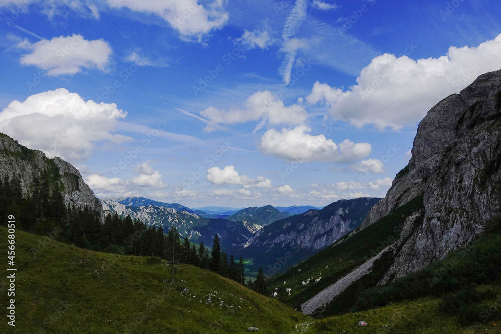 Obraz premium view to a deep valley with mountains and white clouds on the blue sky