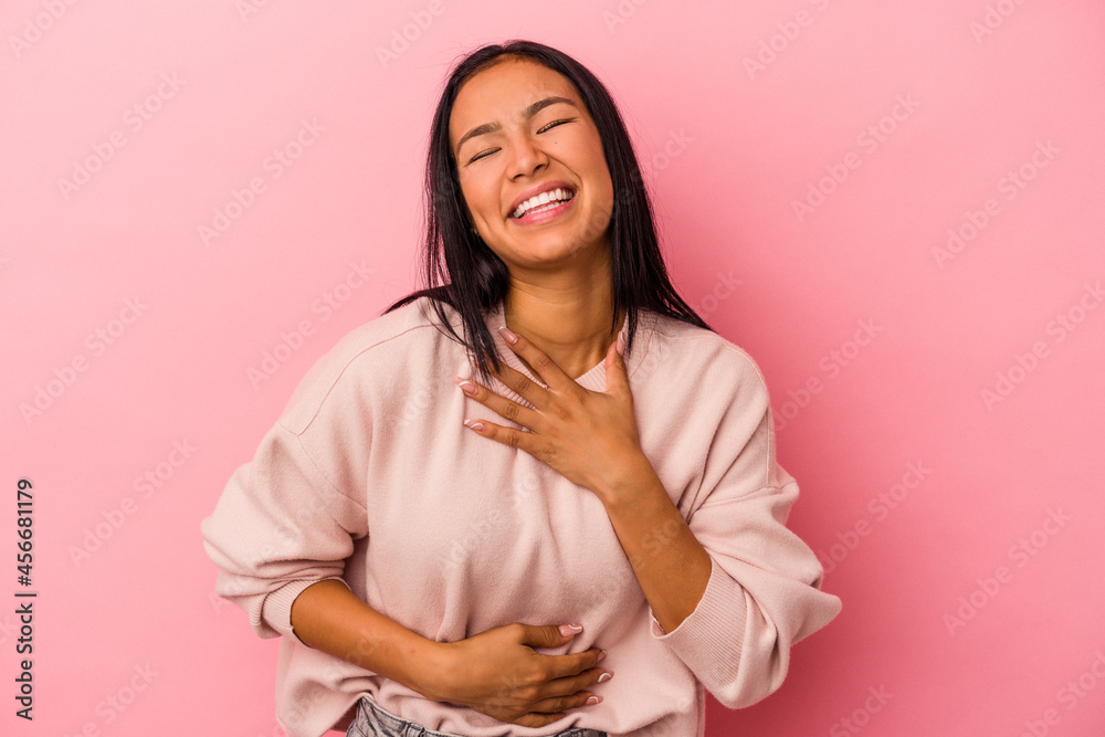Young latin woman isolated on pink background laughs happily and has fun keeping hands on stomach. Young latin woman isolated on pink background laughs happily and has fun keeping hands on stomach.