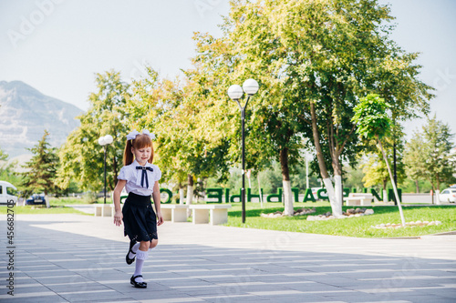 A little girl elementary school student is having fun walking down the street.The child happily goes to school. © Cherkasova Alie