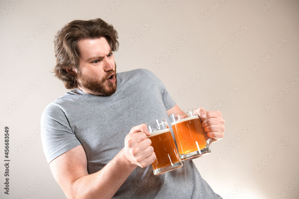 Portrait of a happy young bearded man holding two beer mugs isolated over light gray background Portrait of a happy young bearded man holding two beer mugs isolated over light gray background
