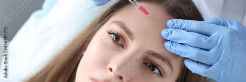 Portrait of woman whose beautician makes injection of botulinum toxin in forehead