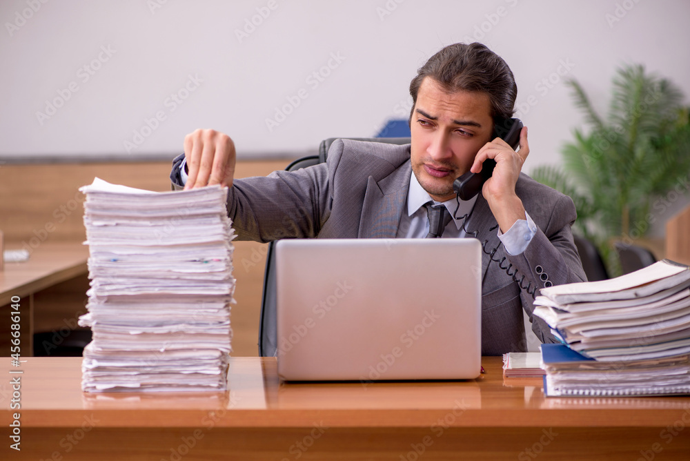 Young male employee and too much work in the office Young male employee and too much work in the office