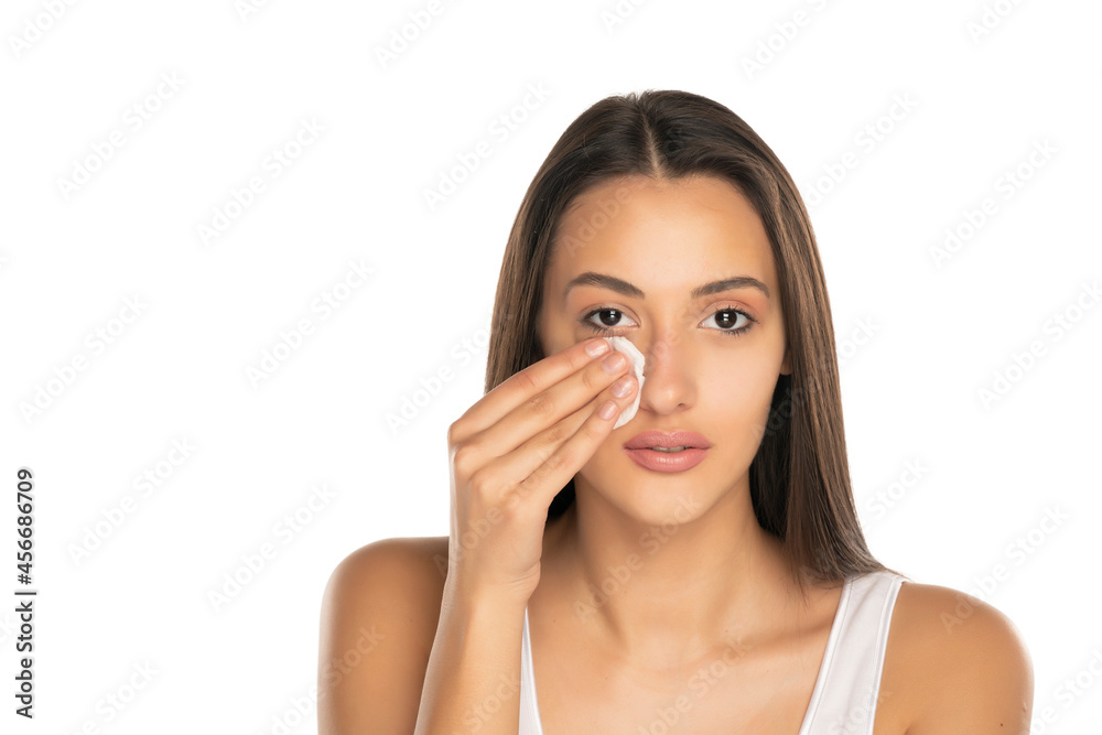 young woman cleans her face with cotton pad young woman cleans her face with cotton pad