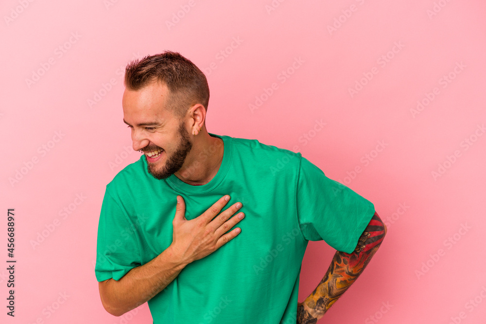 Young caucasian man with tattoos isolated on pink background laughing keeping hands on heart, concept of happiness. Young caucasian man with tattoos isolated on pink background laughing keeping hands on heart, concept of happiness.