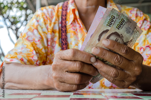 senior woman are holding thai baht banknotes money, banknote money in elderly people hand, savings money and financial business concept