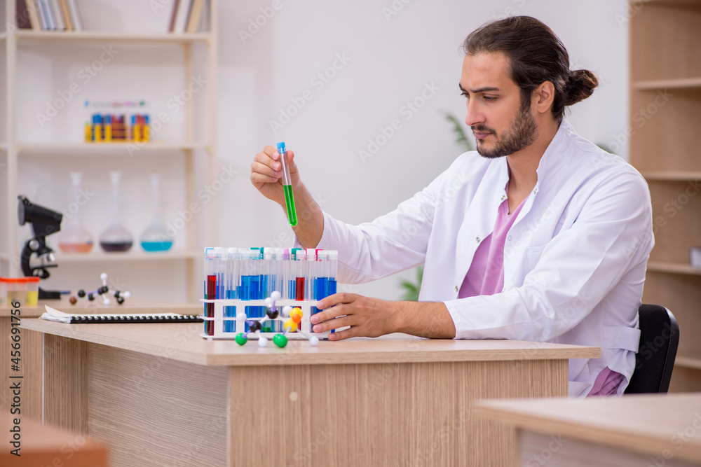 Young male chemist sitting at the desk in the classroom Young male chemist sitting at the desk in the classroom