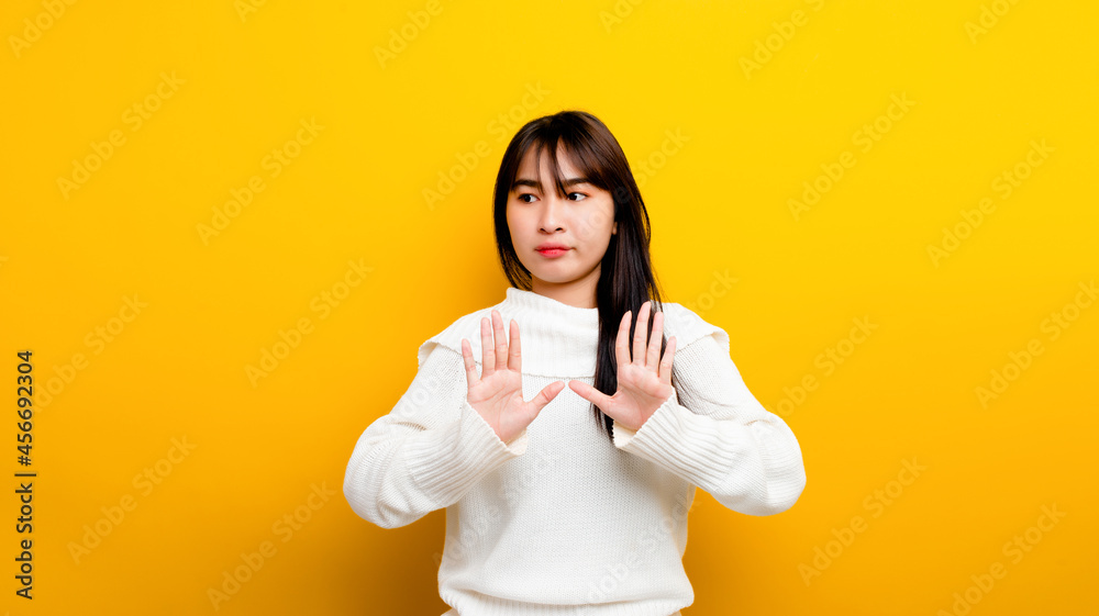 easily upset Portrait of an Asian girl Upset with arms to protect himself looking out lonely on a yellow background easily upset Portrait of an Asian girl Upset with arms to protect himself looking out lonely on a yellow background
