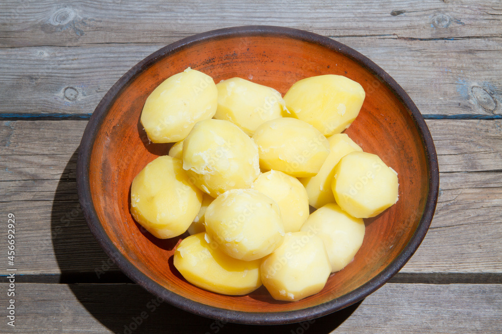 Cooking potatoes on an old wooden table. Raw potatoes in a yellow saucepan on a wooden table. Old wooden boards and vegetables. Cooking potatoes on an old wooden table. Raw potatoes in a yellow saucepan on a wooden table. Old wooden boards and vegetables.