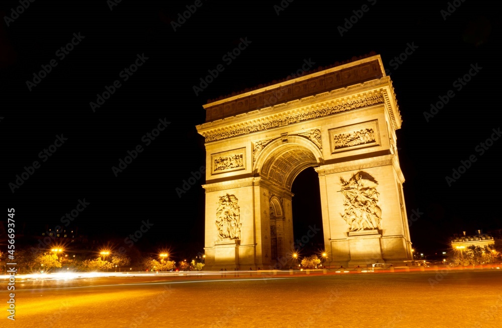 The Arc de Triomphe illuminated on a dark night, with the lights of the cars photographed by a long exposure