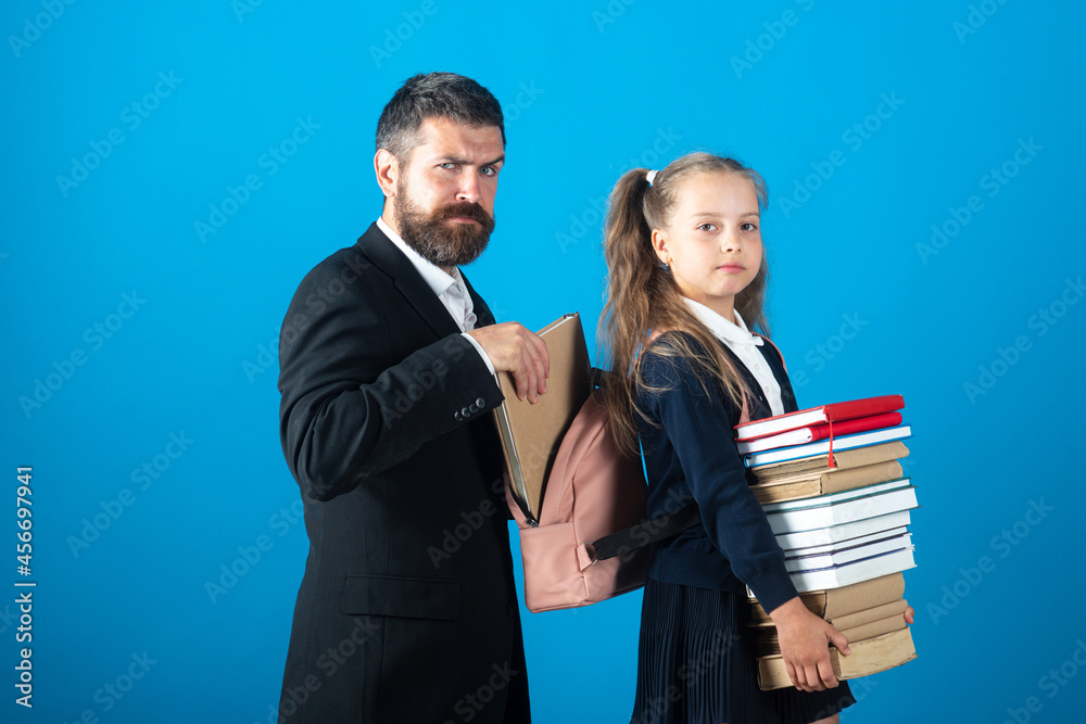 Little school girl hold big stack school textbook notebook books. Father teacher helping to pupil, preparing backpack with school supplies. Educational concept for school. Little school girl hold big stack school textbook notebook books. Father teacher helping to pupil, preparing backpack with school supplies. Educational concept for school.