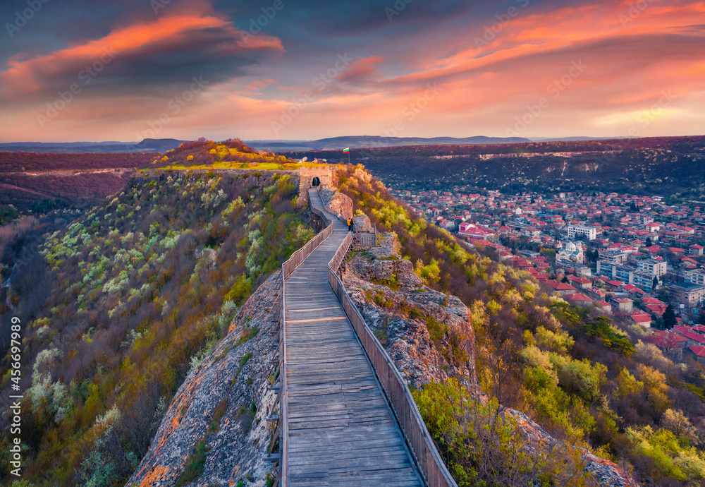 Blooming cherry trees on the hills of Ovech Fortress. Aerial spring cityscape of Provadia town, located in a deep karst gorge along the Provadiya River. Exciting sunset in Bulgaria, Europe.