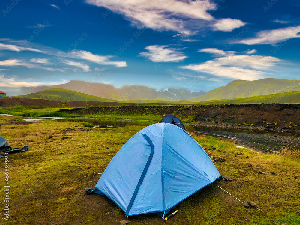 Blue tent on shore of river in mountains