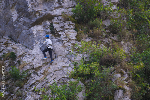 Male hiker in harness climbing mountain