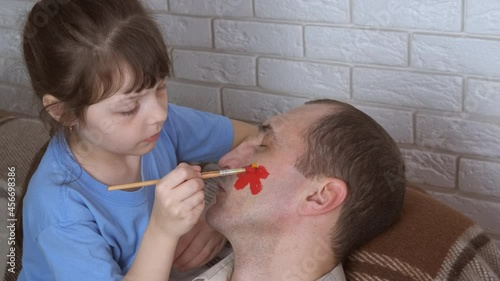 Girl paint dad face. A view of an artictic little girl painting sleeping dad's face in the room. photo
