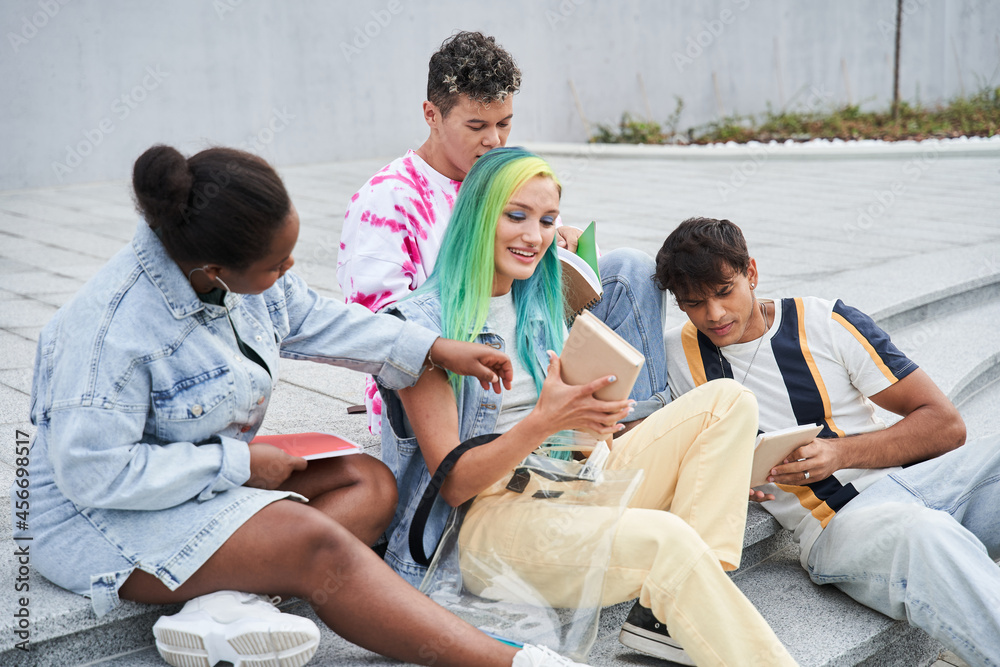 Diverse multiracial students writing something and reading while sitting Diverse multiracial students writing something and reading while sitting
