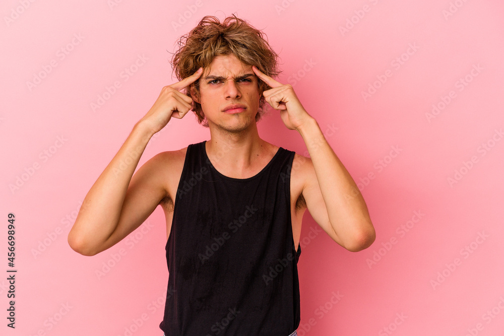 Young caucasian man with make up isolated on pink background focused on a task, keeping forefingers pointing head. Young caucasian man with make up isolated on pink background focused on a task, keeping forefingers pointing head.