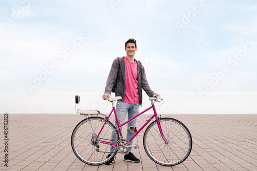 happy young student smiling and holding a bike