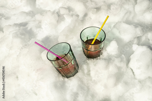 Soda glasses with straws chilling in the snow