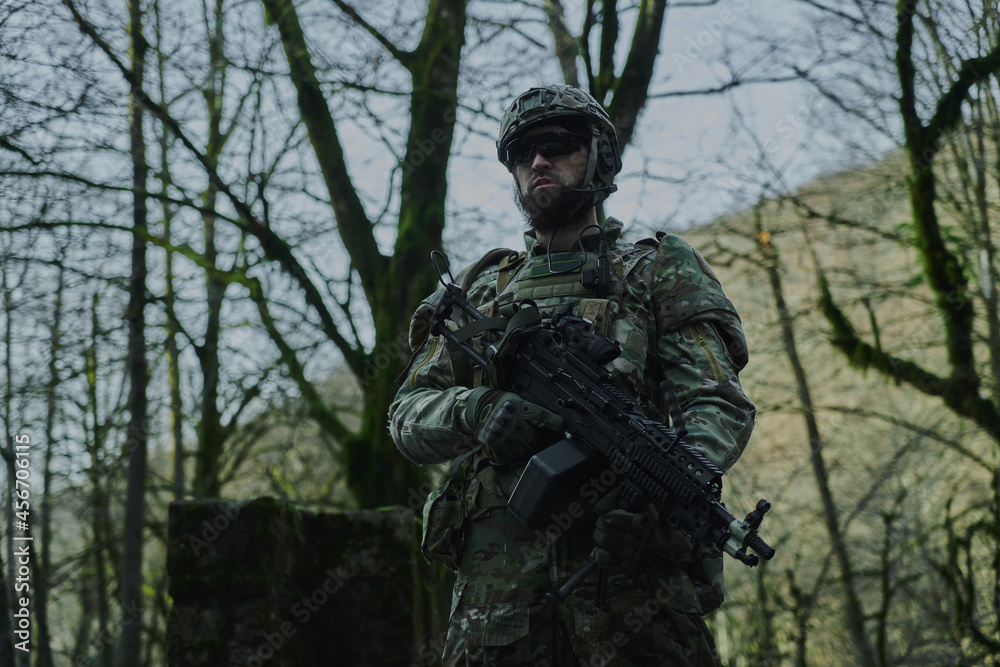 Portrait of airsoft player in professional equipment with machine gun in the forest. Soldier with weapons at war Portrait of airsoft player in professional equipment with machine gun in the forest. Soldier with weapons at war