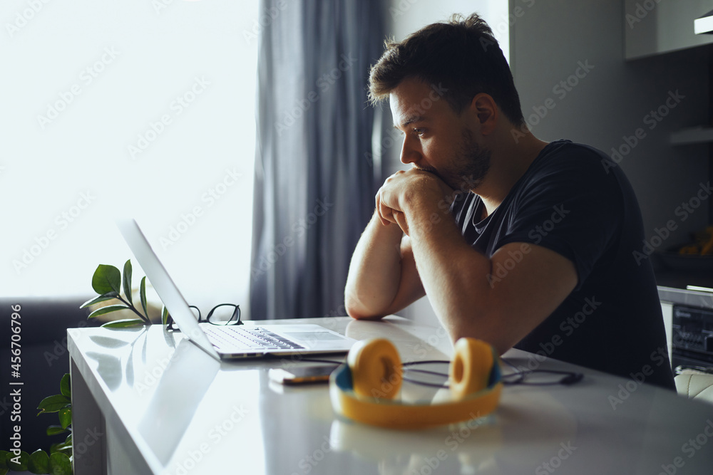 © Davidovici - Concerned serious man lost in thoughts in front of laptop, focused male thinking of problem solution, worried puzzled man looking at laptop screen