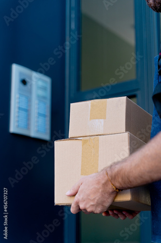 Close up of delivery man delivering parcel box. Courier service concept. Vertical view of unrecognizable rider delivering home a package.