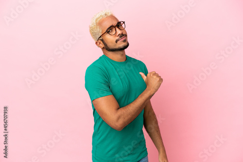 Young Colombian handsome man isolated on pink background proud and self-satisfied