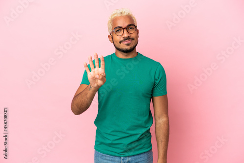 Young Colombian handsome man isolated on pink background happy and counting four with fingers © luismolinero