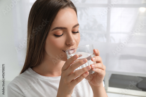 Fototapeta Naklejka Na Ścianę i Meble -  Woman drinking tap water from glass at home, closeup