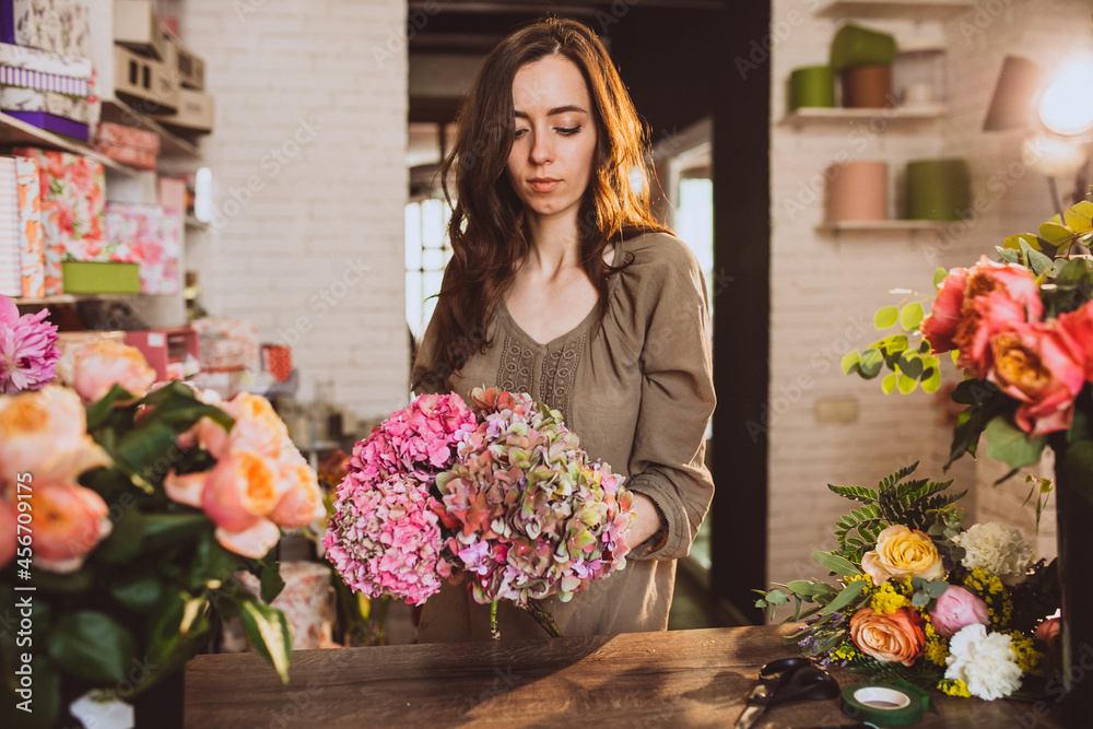 Fototapeta premium Woman florist at her own floral shop taking care of flowers