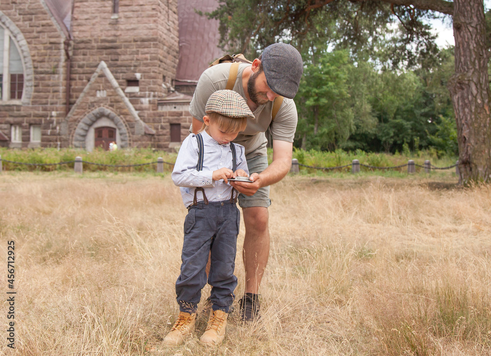 a boy with a dad in vintage clothes holds an old compass in his hands.