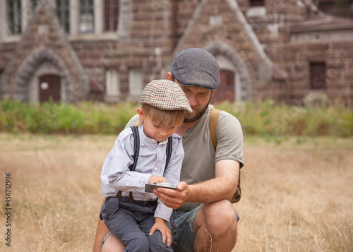 a boy with a dad in vintage clothes holds an old compass in his hands