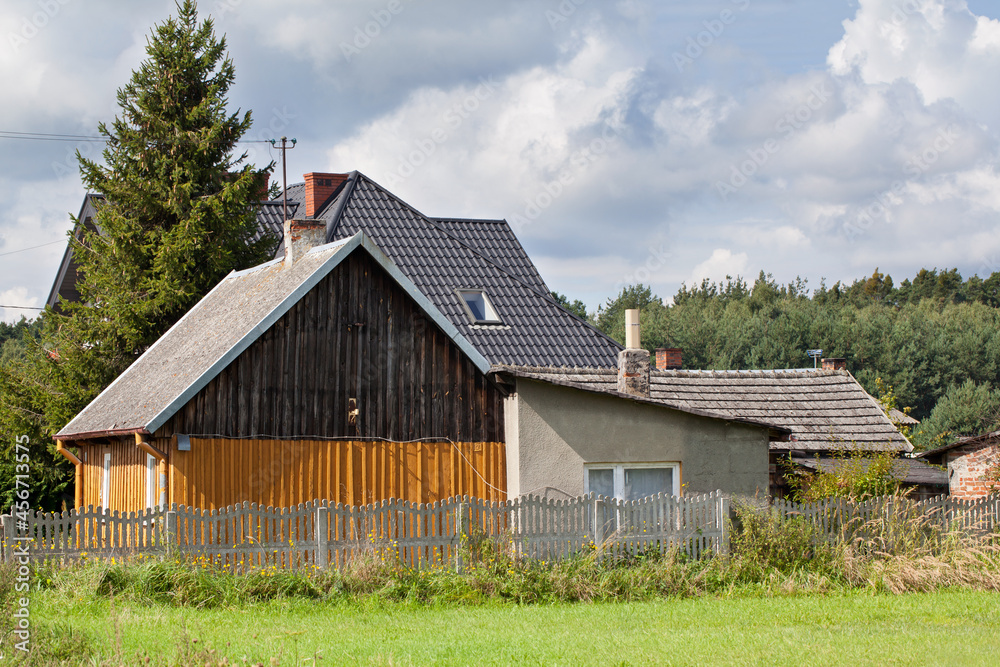 Traditional rural buildings, against a background of sky and forest.