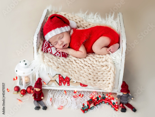 Newborn in santa suit resting on bed