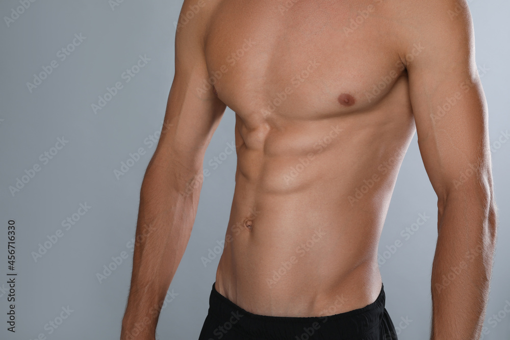 Shirtless man with slim body on grey background, closeup Shirtless man with slim body on grey background, closeup
