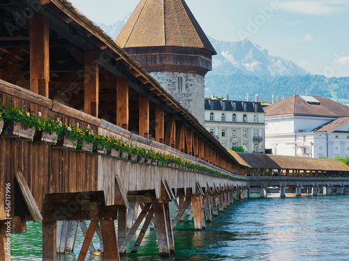 Wooden footbridge "Kapellbrücke" (literally chapel bridge) over the Reuss river with water tower in the city of Lucerne, Switzerland. Flower boxes on the façade of the bridge