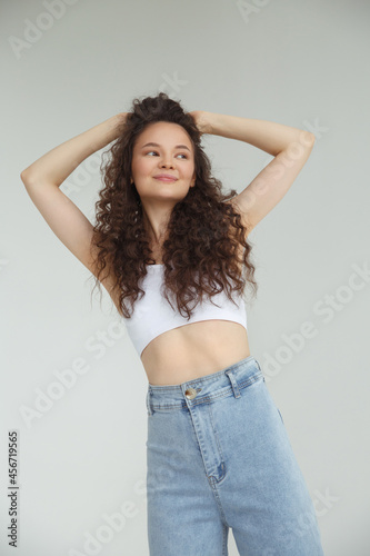 A cute natural girl with lush curls on a light gray background.