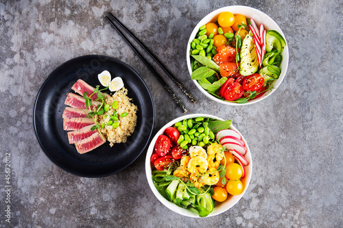Two plates with poke and a plate with fried tuna on a gray background