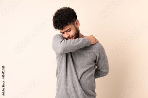 Young Moroccan man isolated on beige background suffering from pain in shoulder for having made an effort © luismolinero