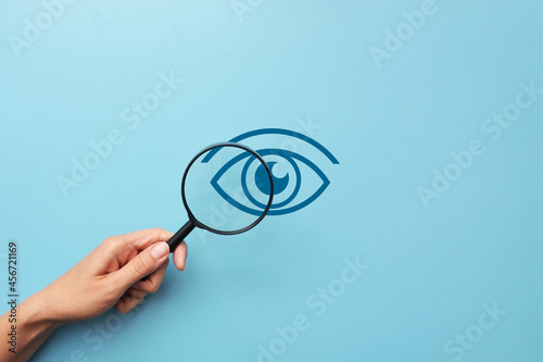 A person examines the eye through a magnifying glass. Symbol for the diagnosis of eye diseases photo