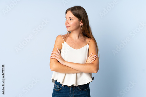 Young Lithuanian woman isolated on blue background looking to the side
